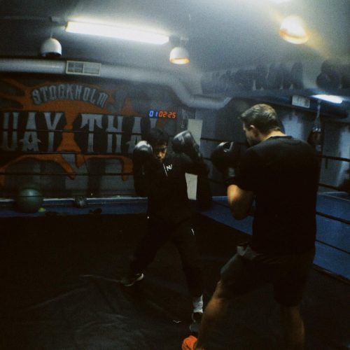 En pojke och man tränar thaiboxning på Stockholm Muay Thai